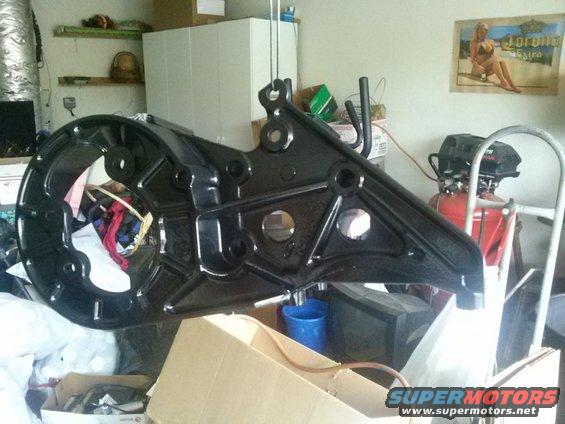 black painted metal part hanging in a garage, air compressor and poster in background