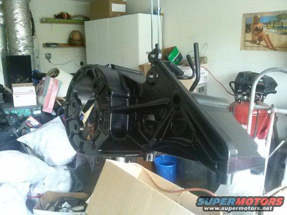 Black metal part hanging from hoist in cluttered garage