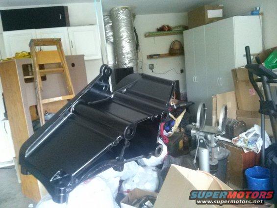 Black metal part in a cluttered garage