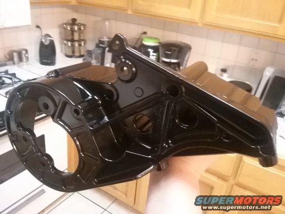 Black metal bracket held in hand, with kitchen cabinets and appliances in background