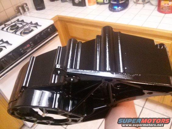 Black metal part held in hand, with a kitchen stove in background