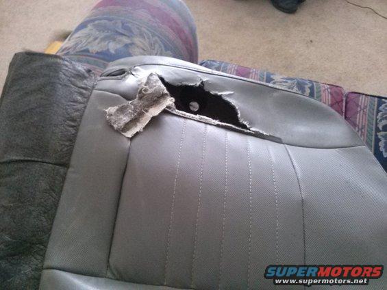 Torn gray car seat with stuffing showing through a large rip