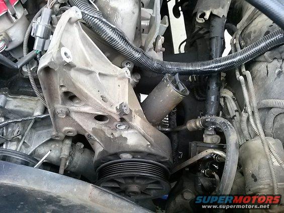 Engine pump assembly with pulley and hoses. Some grease and dirt visible