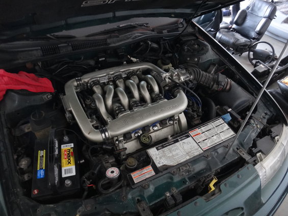1993 Ford Taurus engine bay with V6 engine, battery, and maintenance information sticker