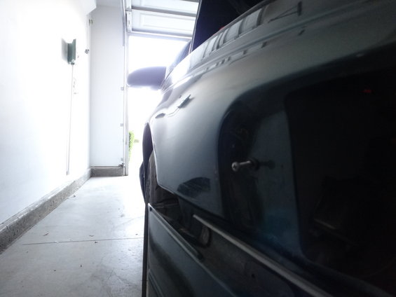 Car parked in a garage, side view showing rear quarter panel and door