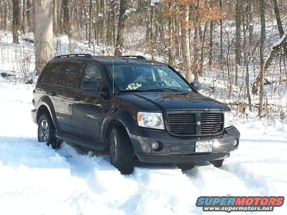Black SUV stuck in snow, front 3/4 view. License plate reads MC5 HOM