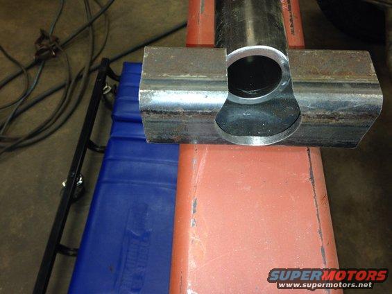 Close-up of a metal pipe joint with a circular opening, resting on a red surface