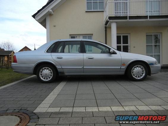 Silver sedan parked in front of a house. Side view