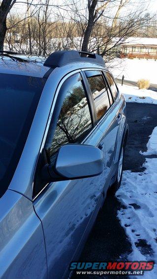 Silver SUV side view with roof rack and window visors, parked in snow