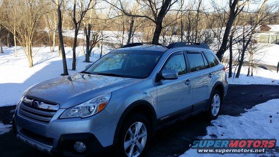 Silver 2014 Subaru Outback with dark window visors parked in snow