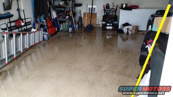garage interior with ladders, snowblower, and a car partially visible on the right