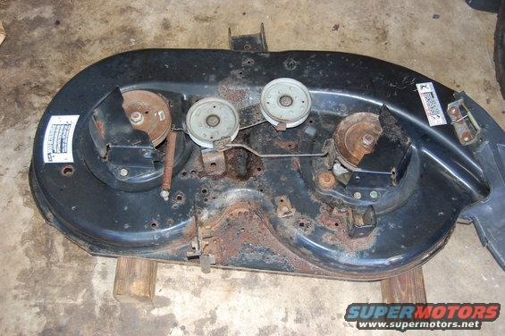 Rusted mower deck with three pulleys and drive belt tensioner mechanism