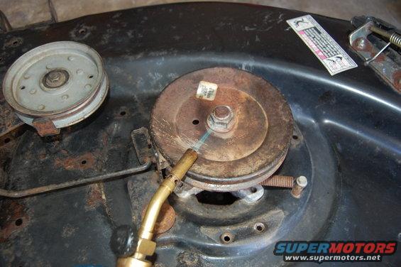 Close-up of a lawn mower deck pulley with a torch aimed at it