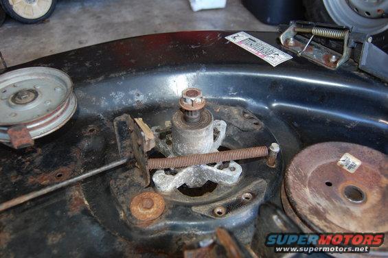 Rusty lawn mower deck with pulley, spindle, and adjustment screw