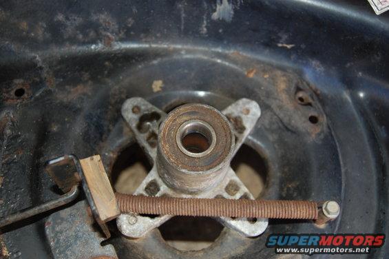 Close-up of a rusty lawn mower spindle bearing with a spring and lever mechanism