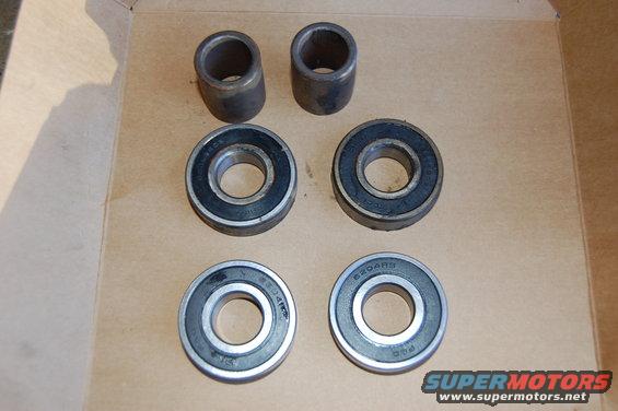 Four ball bearings and two metal bushings on a cardboard surface
