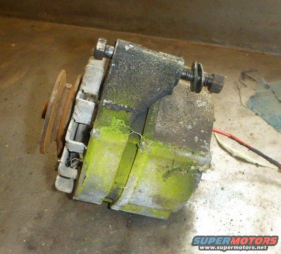 Alternator with pulley and wires, covered in grime and green residue