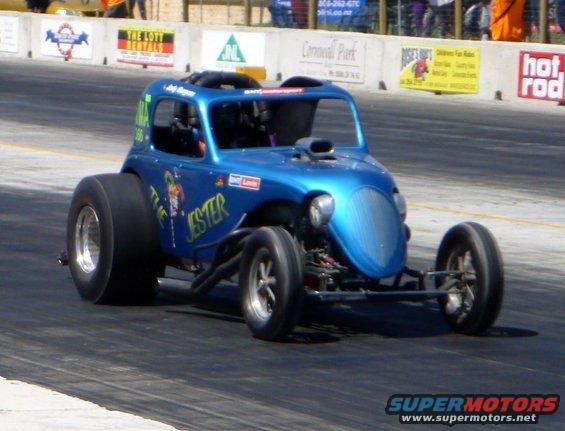blue drag car with 'The Jester' painted on side, racing on track