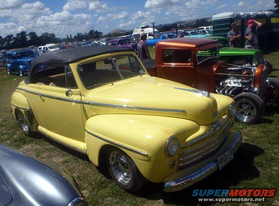 Yellow convertible car with black top, chrome trim, and a license plate reading '4BDLUX'