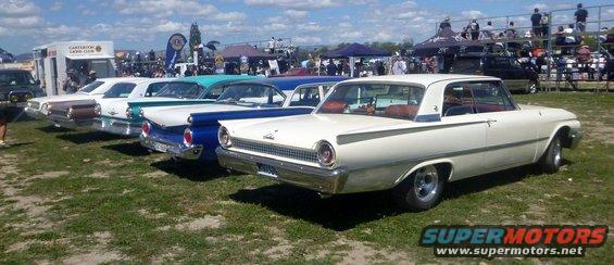 White 1960 sedan, 3q-front view. Other classic cars lined up