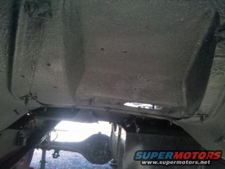 Underside of a vehicle, showing frame and rear axle. Supermotors.net logo visible