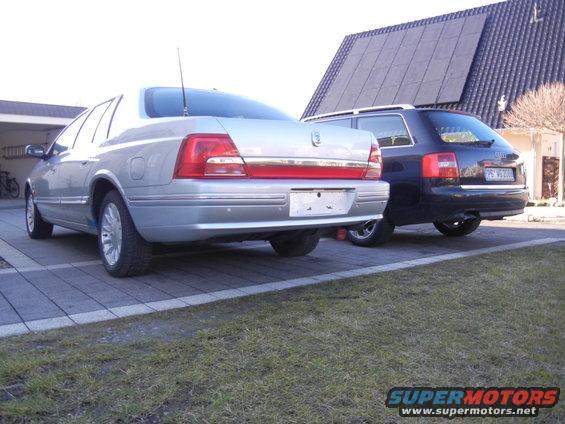 Silver sedan parked next to a black wagon, rear view