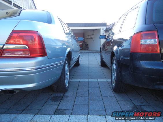 Light blue sedan and black wagon parked side-by-side in a paved driveway