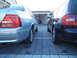 1999 Ford Fairlane - Two cars are parked in a driveway, one light blue sedan and one black wagon.