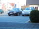 1999 Ford Fairlane - A silver sedan is parked in a driveway next to a dark blue Audi wagon.