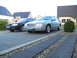 1999 Ford Fairlane - Two sedans are parked in a driveway in front of houses.
