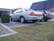 1999 Ford Fairlane - This silver sedan, possibly a 1999 Ford Fairlane, is parked in a driveway next to a dark SUV.