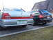 1999 Ford Fairlane - Two cars parked side-by-side in a driveway, one silver sedan and one black Audi wagon.