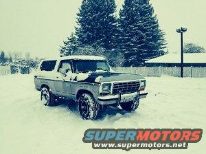 Gray 1978 Ford Bronco with black hood stripe parked in snow, front quarter view