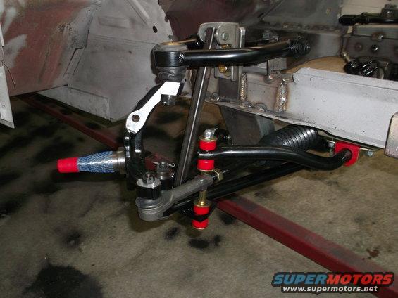 Close-up of a car's front suspension with red and black components, including tie rods and control arms