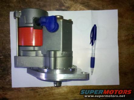 Engine part with red cylinder and blue cap, next to a pen