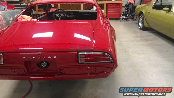 Red Pontiac Firebird rear view, showing 'PONTIAC' badging and taillights