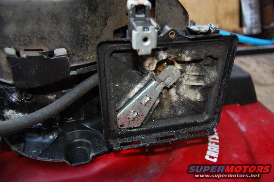 Close-up of a Craftsman lawnmower's dirty air filter housing and linkage