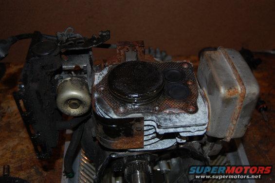 Close-up of a dirty engine cylinder head with valves and a carburetor