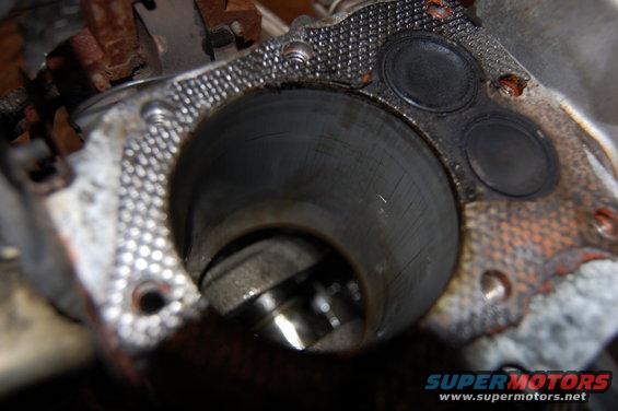 Engine cylinder with visible scoring and two valves above, close-up view