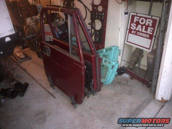 Red Jeep CJ doors and a blue door in a garage with a 'For Sale' sign