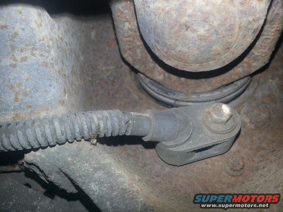 ABS sensor and protective wiring conduit attached to a rusty suspension part