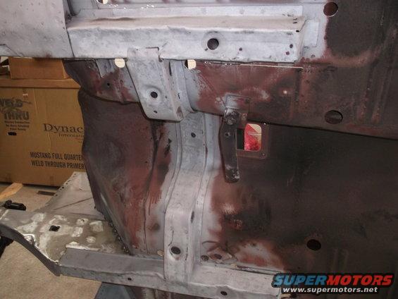 Car frame section with rust and primer, showing mounting points