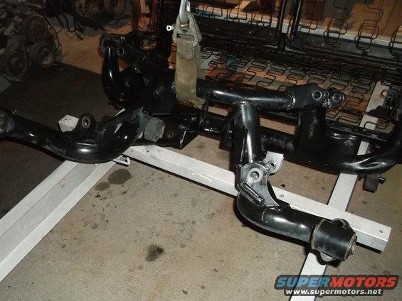 Black painted car frame parts on a metal stand, with seat springs in the background