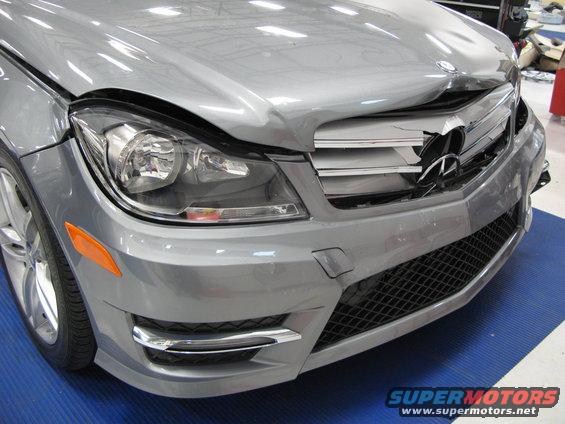 Damaged silver Mercedes-Benz front end with broken grille and headlight