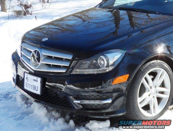 Black Mercedes-Benz C-Class front end with grille and headlights visible, parked in snow. License plate reads 61119U
