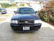 2007 Ford Crown Victoria - A black 2007 Ford Crown Victoria is parked in a driveway with a green SUV in the background.
