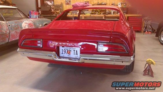 Rear view of a red 1972 Pontiac Trans Am with a Georgia license plate that reads '1972 TA'. Another car is visible to the left