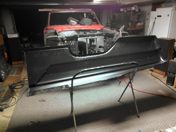 Black car rear bumper panel on a stand in a garage
