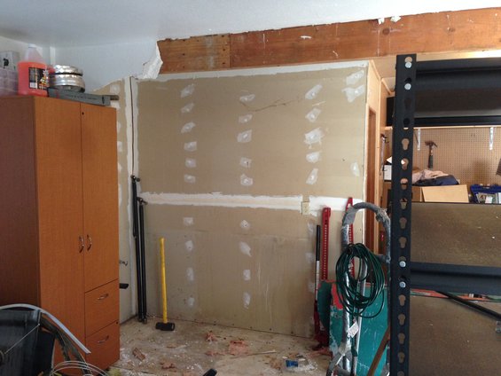 Garage interior with a tall cabinet, tools, and unfinished wall
