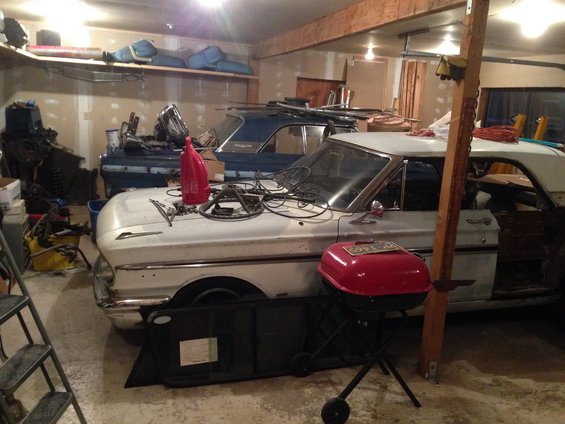 1964 Ford Fairlane and a blue car in a cluttered garage
